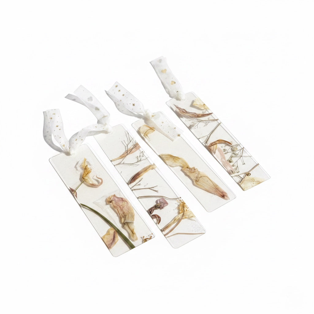 The J.M Press Silvered Forest Trio bookmarks featuring dried flowers and leaves encased in clear resin with white ribbon ties.