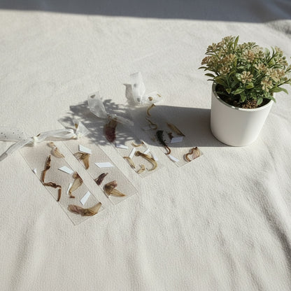The J.M Press Silvered Forest Trio bookmarks with dried flowers and leaves encased in clear resin. Soft grey and natural tones.